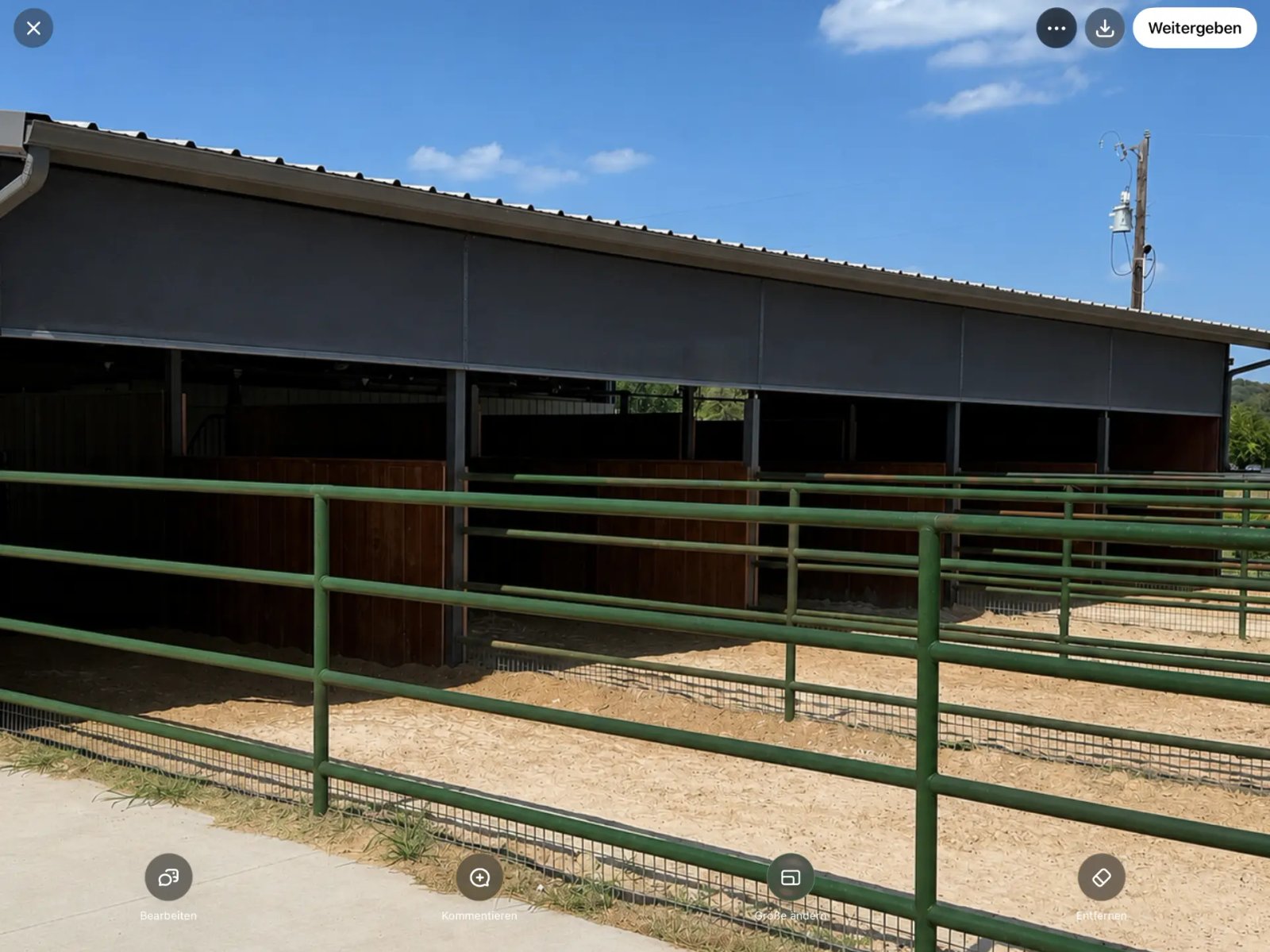 Real exterior photo of a horse barn with installed permanent screens, alternate view.