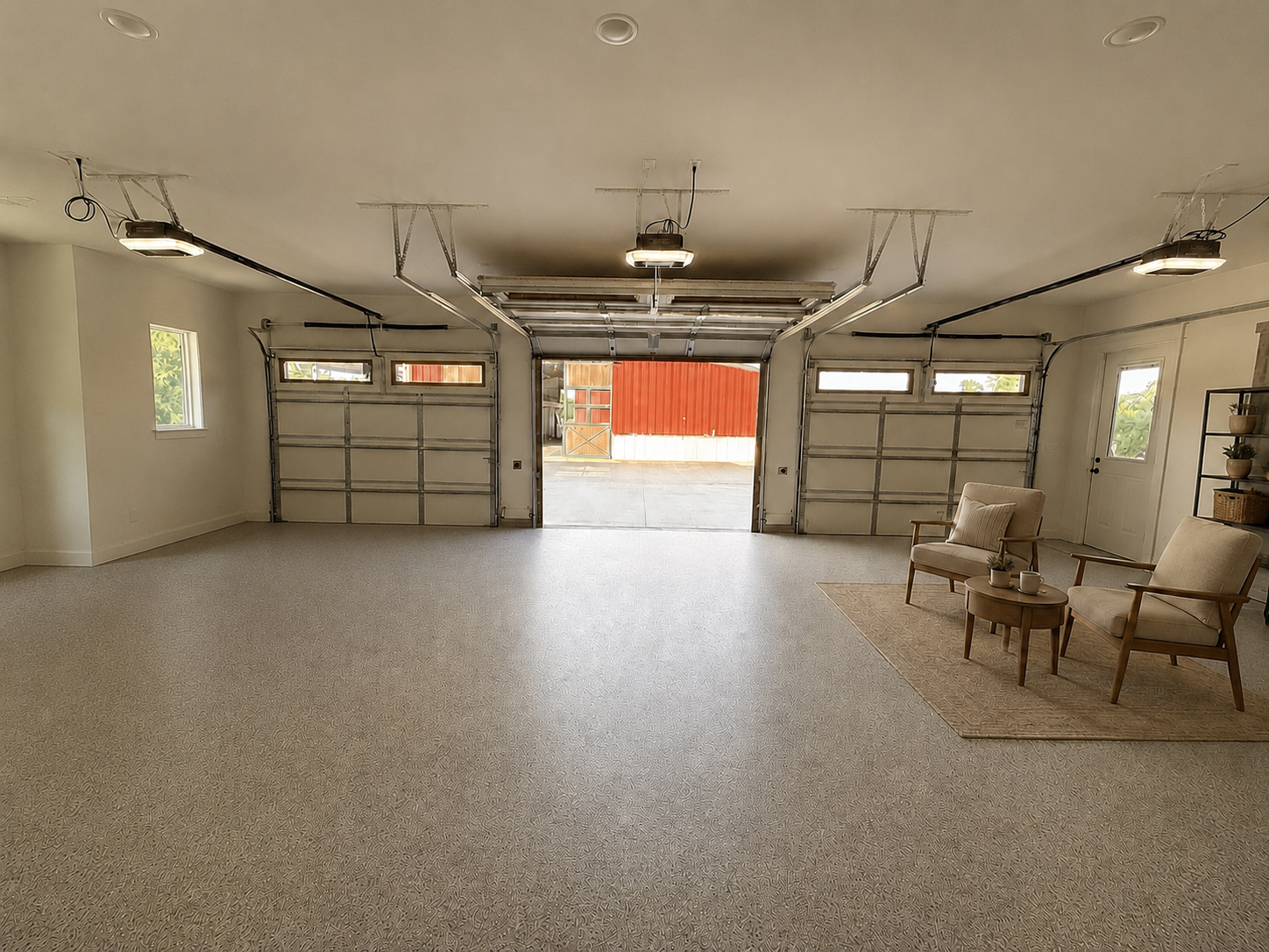 A spacious residential garage interior with two chairs, a small table, and a sports car, the open door revealing daylight beyond.