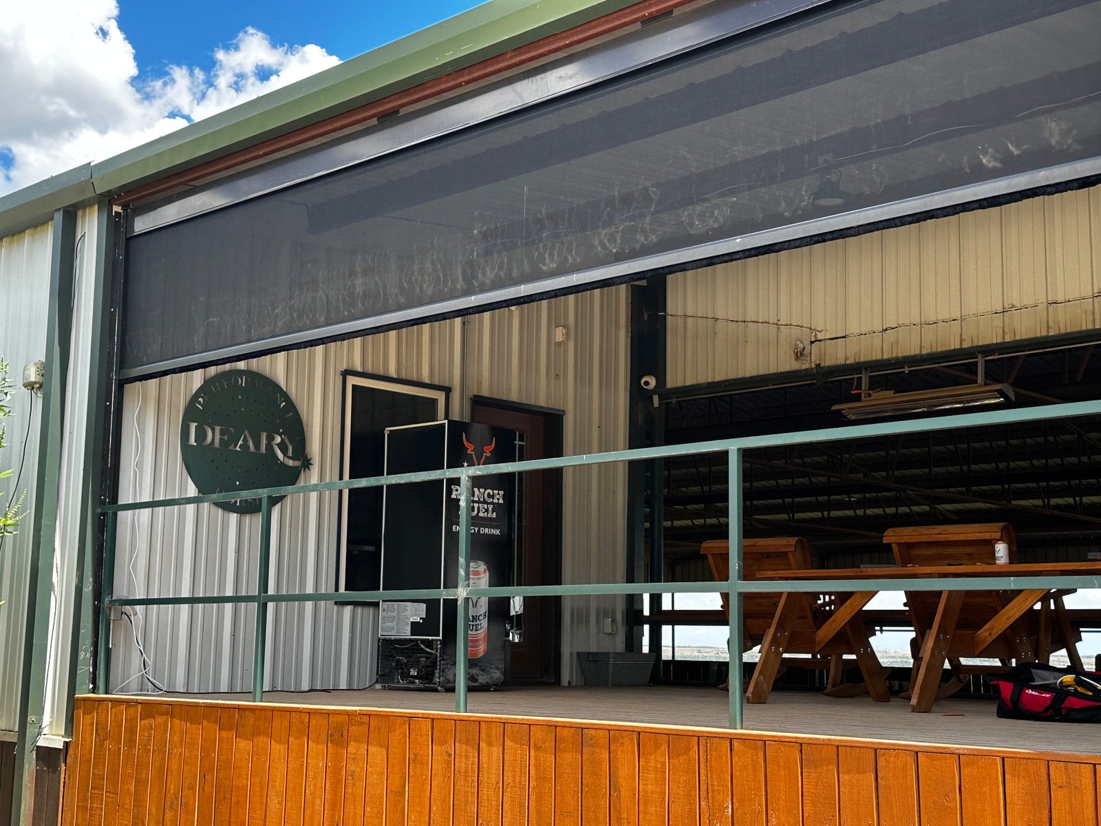 Real exterior photo of a ranch building with retractable screens installed across the opening.